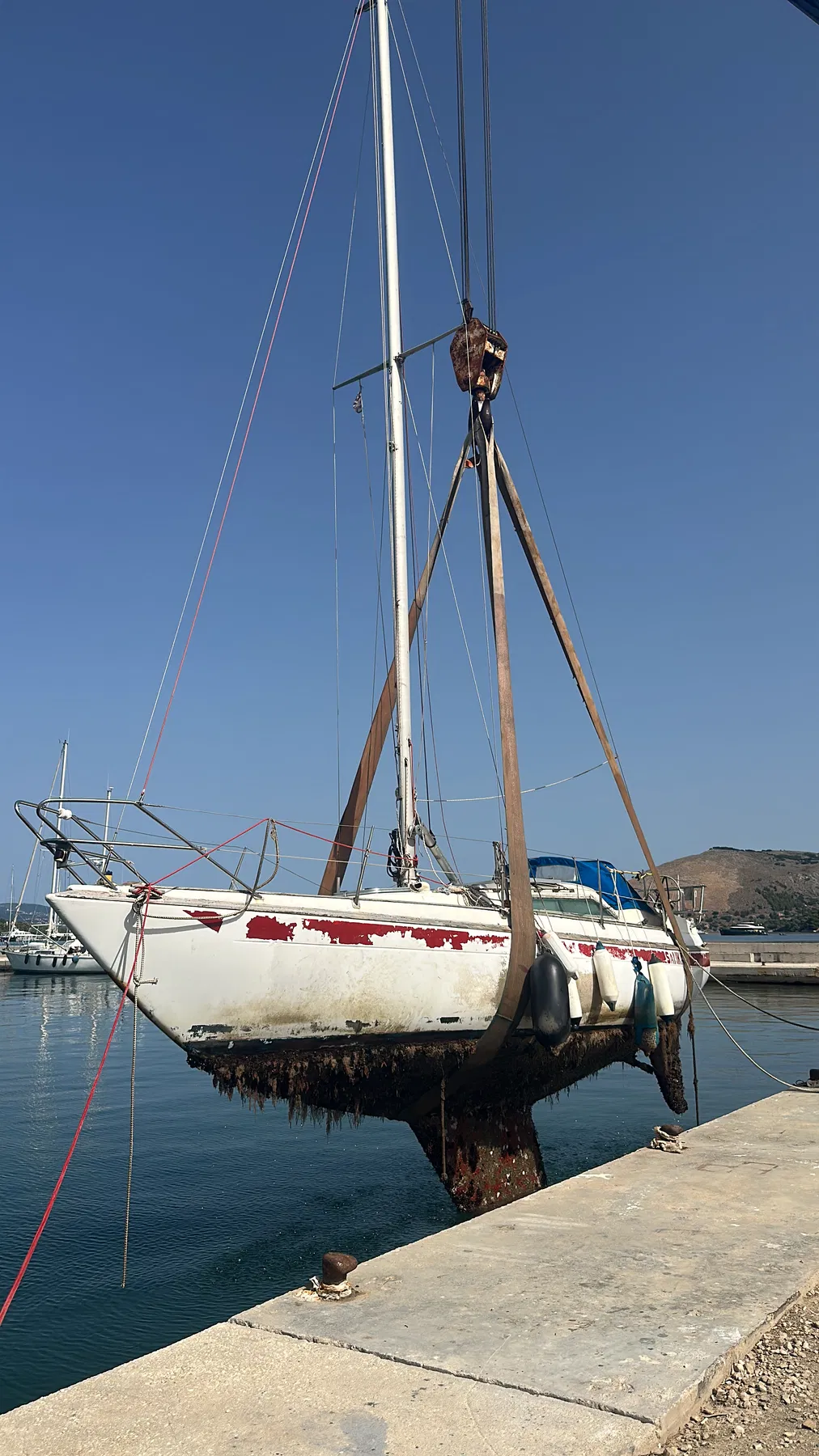 Bateau endommagé SANKARA — vue latérale à terre lors de la sortie d’eau ; la bande rouge et les œuvres vives sont visibles.
