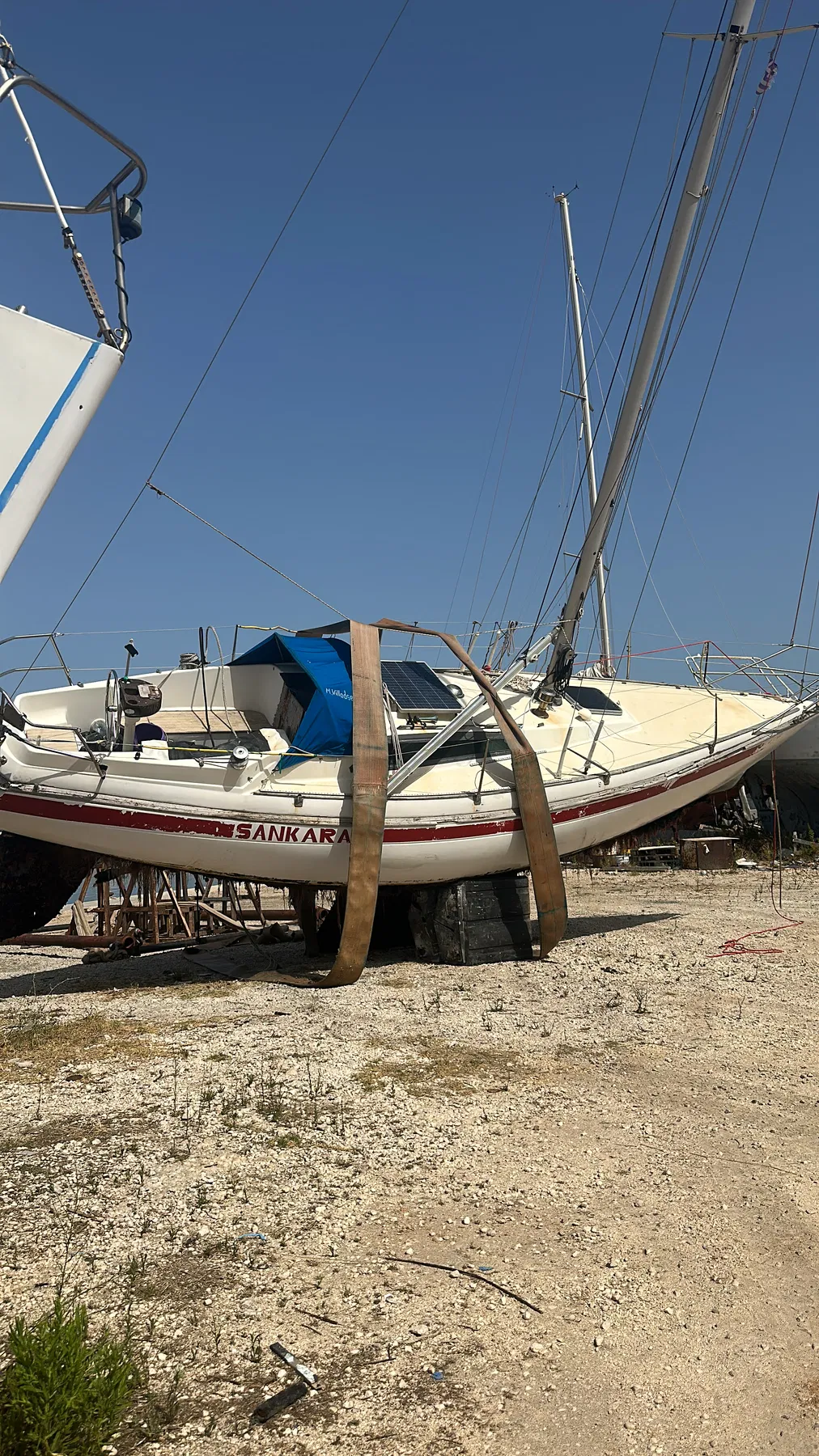 Bateau endommagé SANKARA — vue d’ensemble à terre, nom du bateau visible et coque calée.