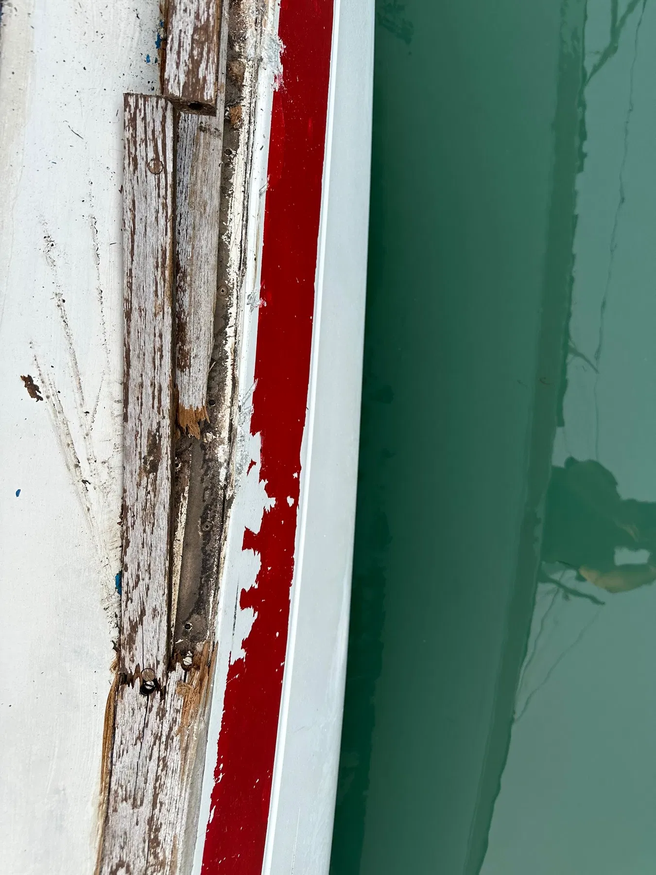 Bateau endommagé SANKARA — gros plan d’un bord en bois endommagé ou ouvert à la jonction pont-coque.