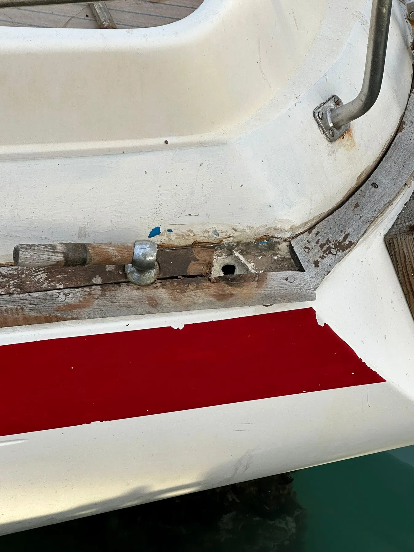 Bateau endommagé SANKARA — accastillage du pont arrière avec bois apparent et arraché autour de la fixation.