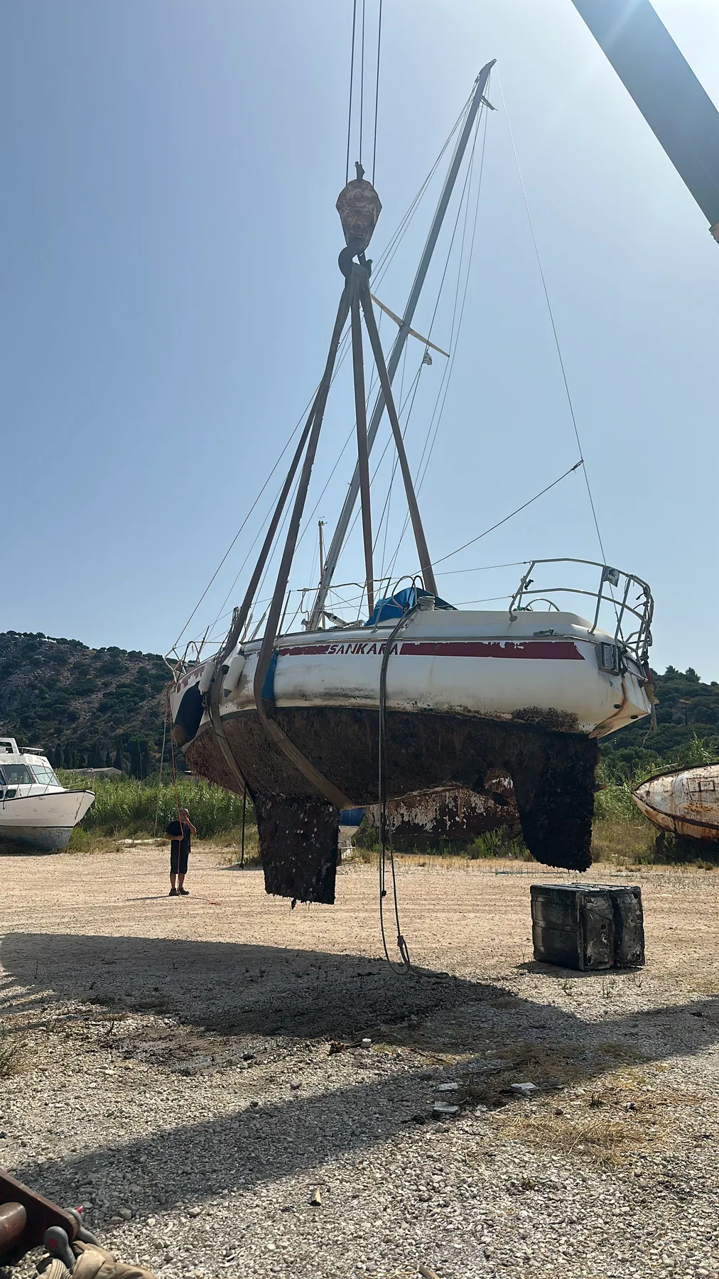 Bateau endommagé SANKARA — vue à terre depuis l’arrière, montrant coque, quille et calage.