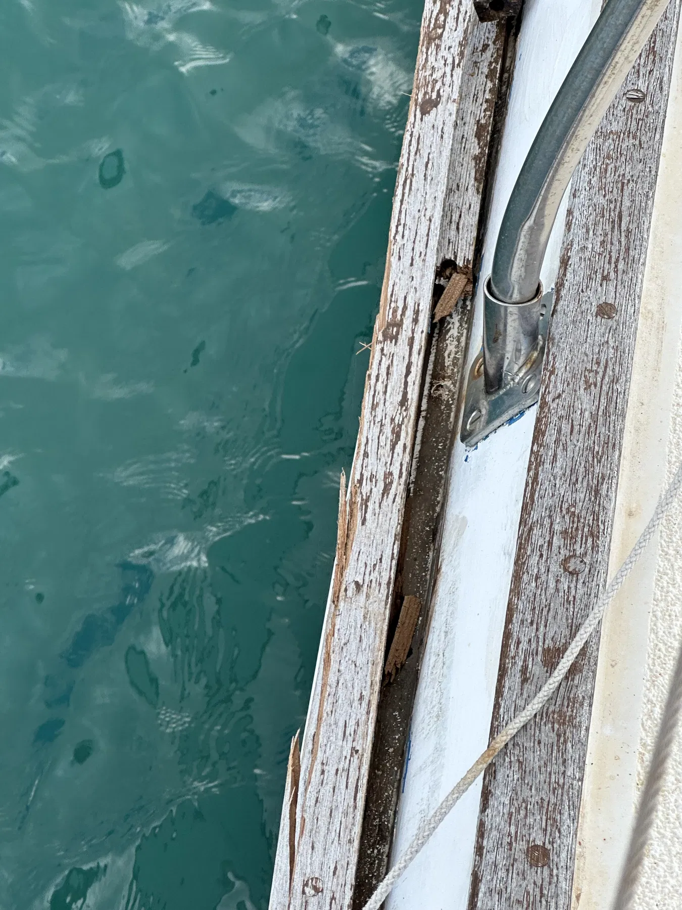 Bateau endommagé SANKARA — gros plan du bord de pont en bois et d’un accastillage métallique.