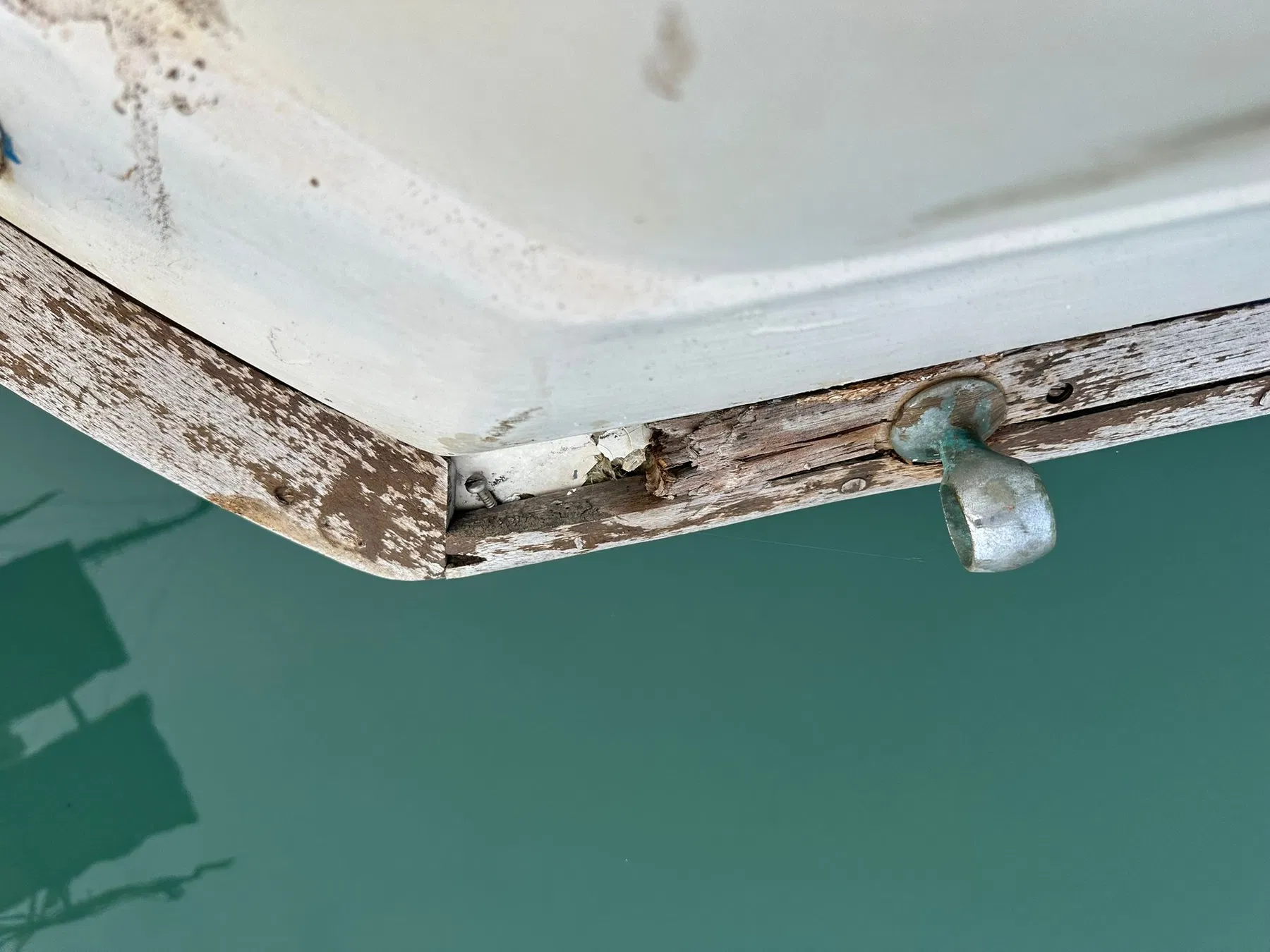 Bateau endommagé SANKARA — bord arrière avec accastillage, entourage en bois et ouverture visible dans la zone de fixation.